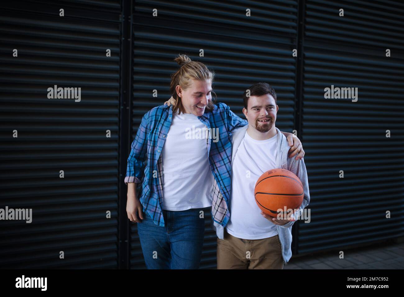 Man with down syndrome playing basketball outdoor with his friend