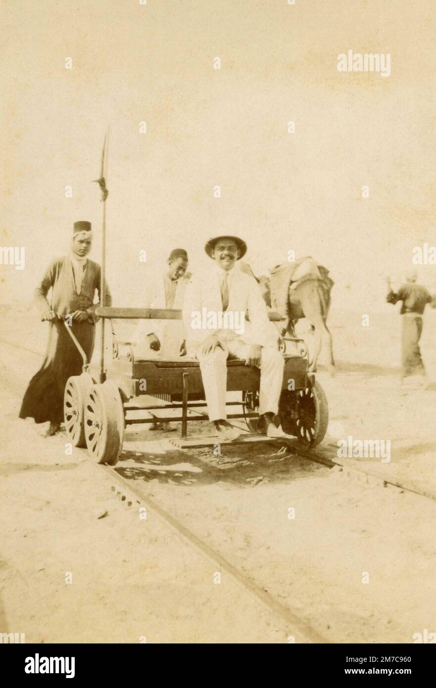 Man onboard a railway trolley pushed by locals, Egypt 1920s Stock Photo