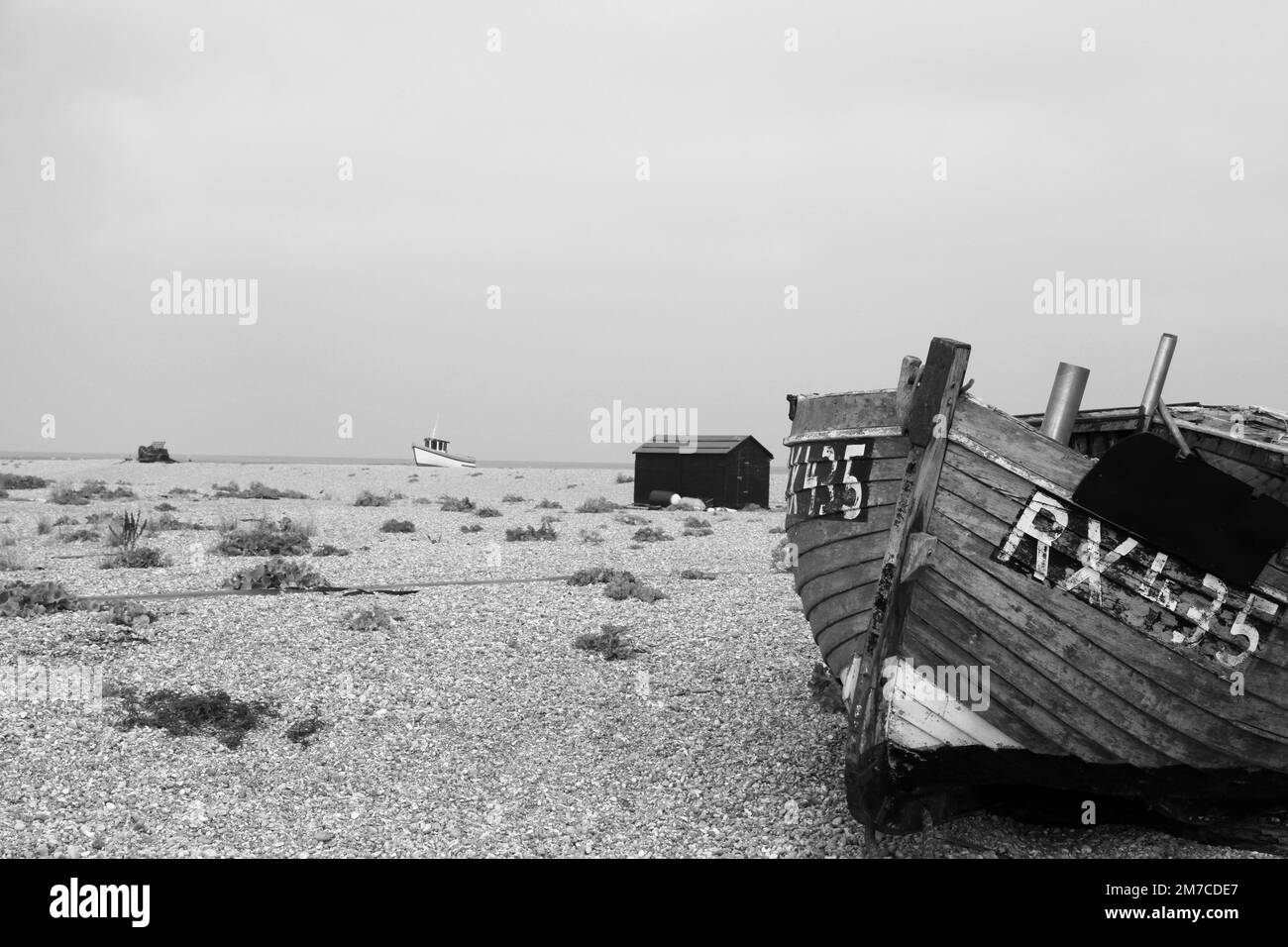 Black and white image of abandoned fishing boat on Dungeness Beach Kent England Stock Photo