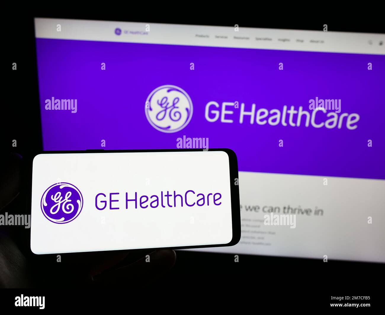 Person holding smartphone with logo of US company GE HealthCare Technologies Inc. on screen in front of website. Focus on phone display. Stock Photo