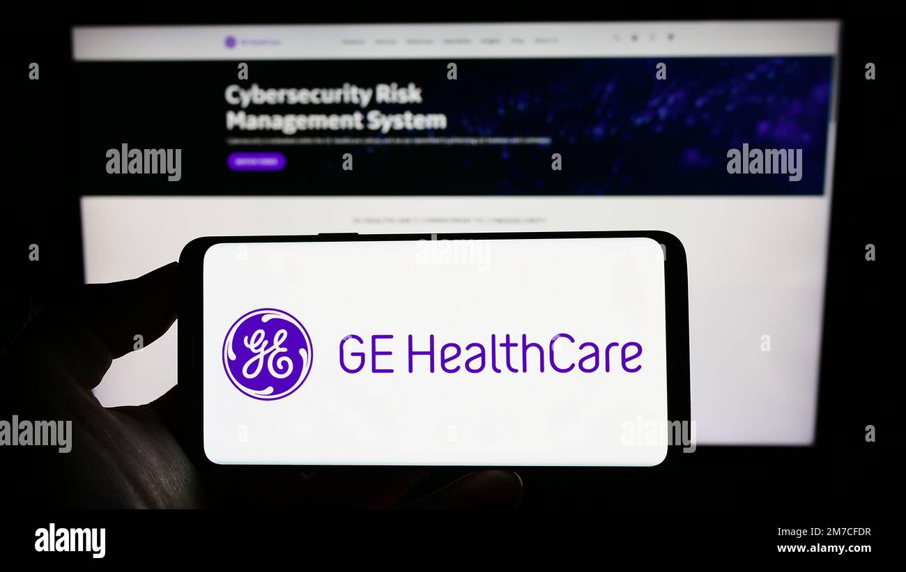 Person holding cellphone with logo of US company GE HealthCare Technologies Inc. on screen in front of business webpage. Focus on phone display. Stock Photo
