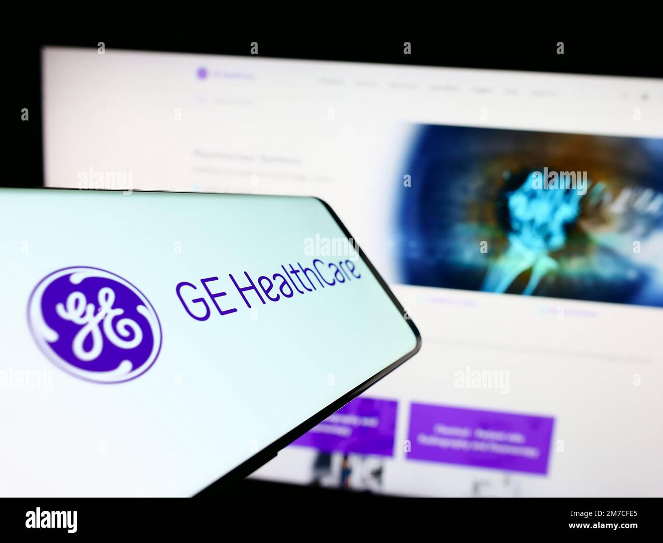 Mobile phone with logo of American company GE HealthCare Technologies Inc. on screen in front of website. Focus on center-right of phone display. Stock Photo