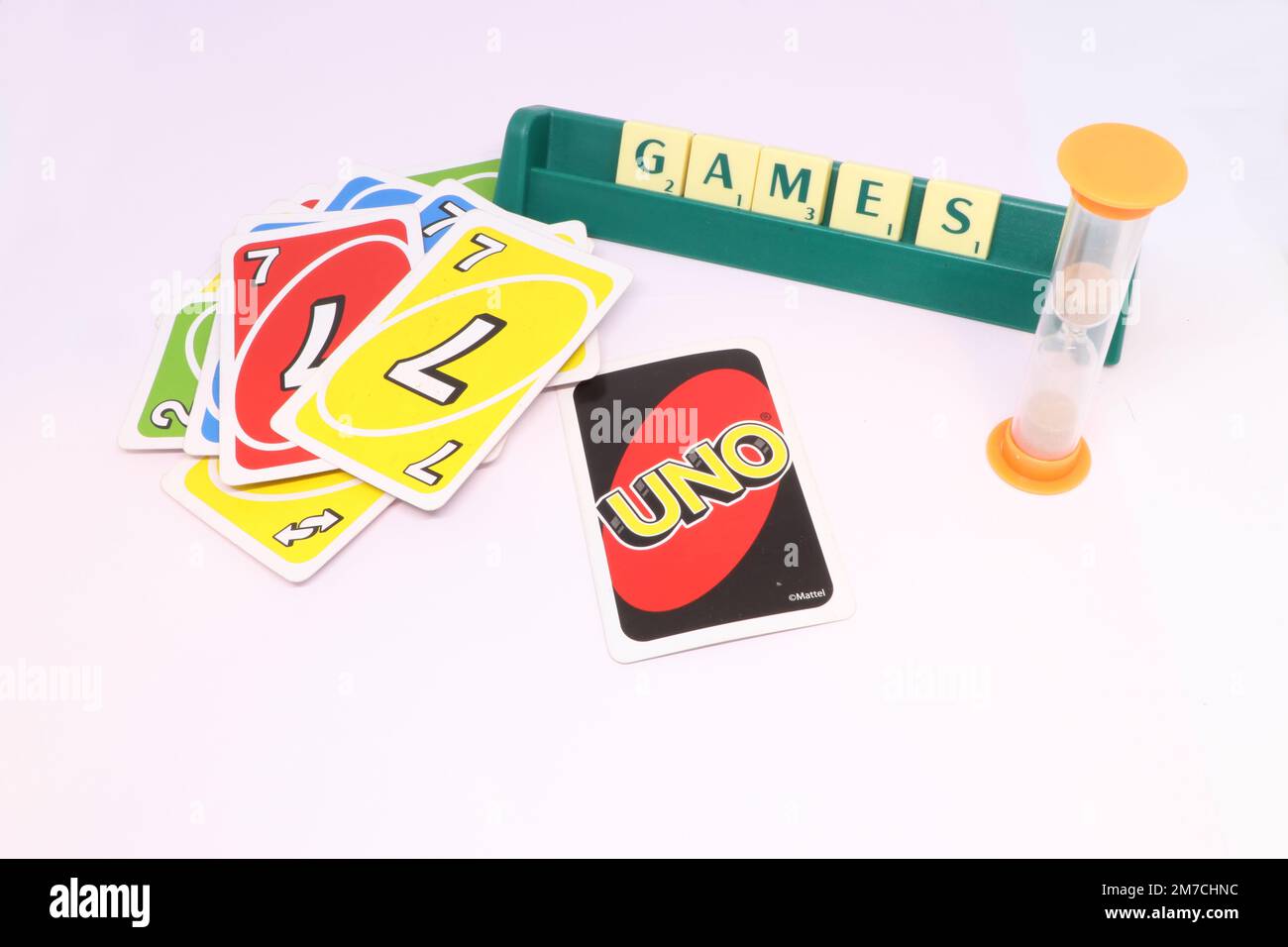 A concept of a games night showing the word 'games' spelled in scrabble tiles on a tile rack. UNO cards are spread out in a pile with a sand timer. Stock Photo