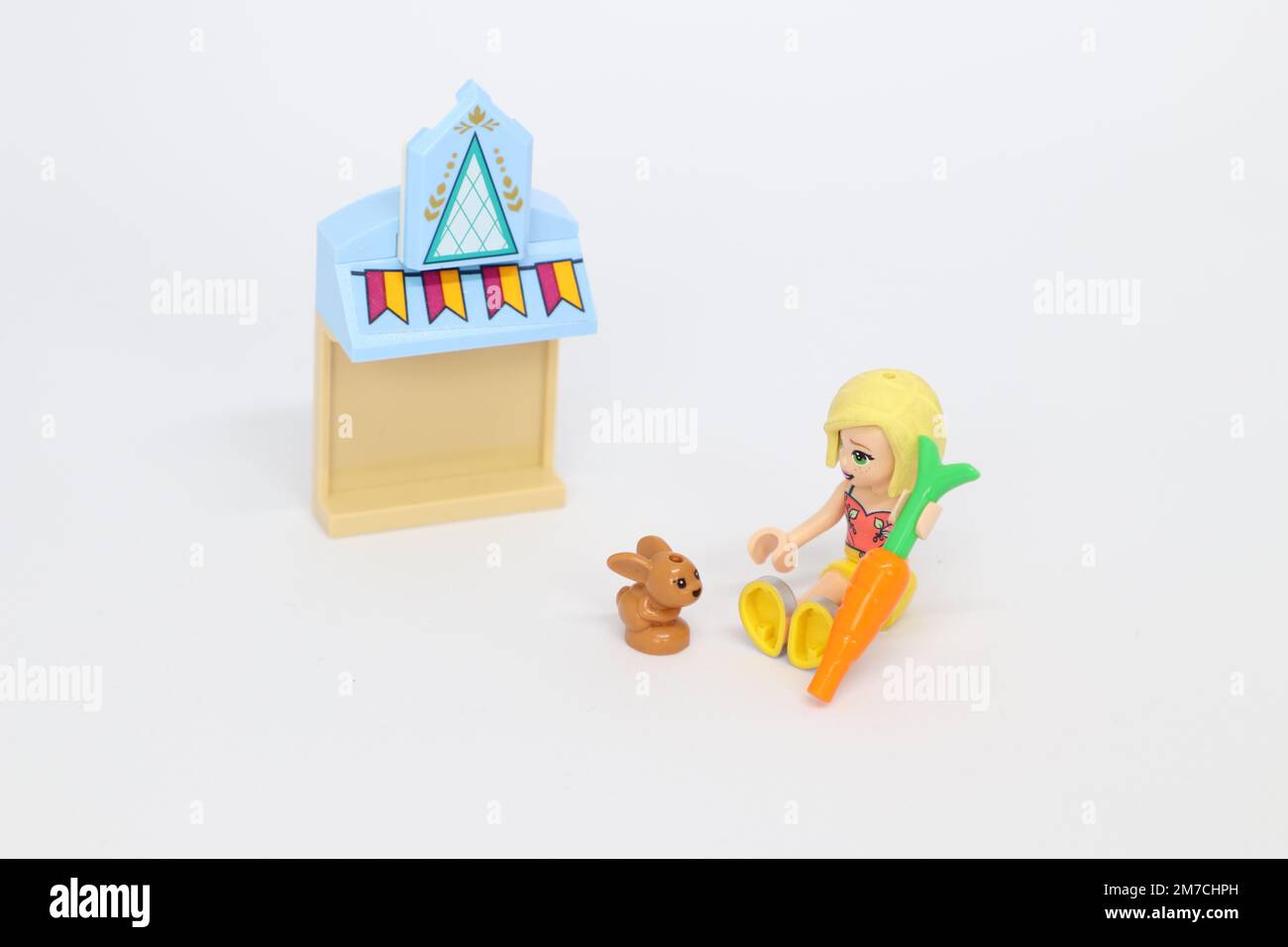 a lego mini figure girl holding a carrot feeding a pet bunny by a building with bunting on Stock Photo