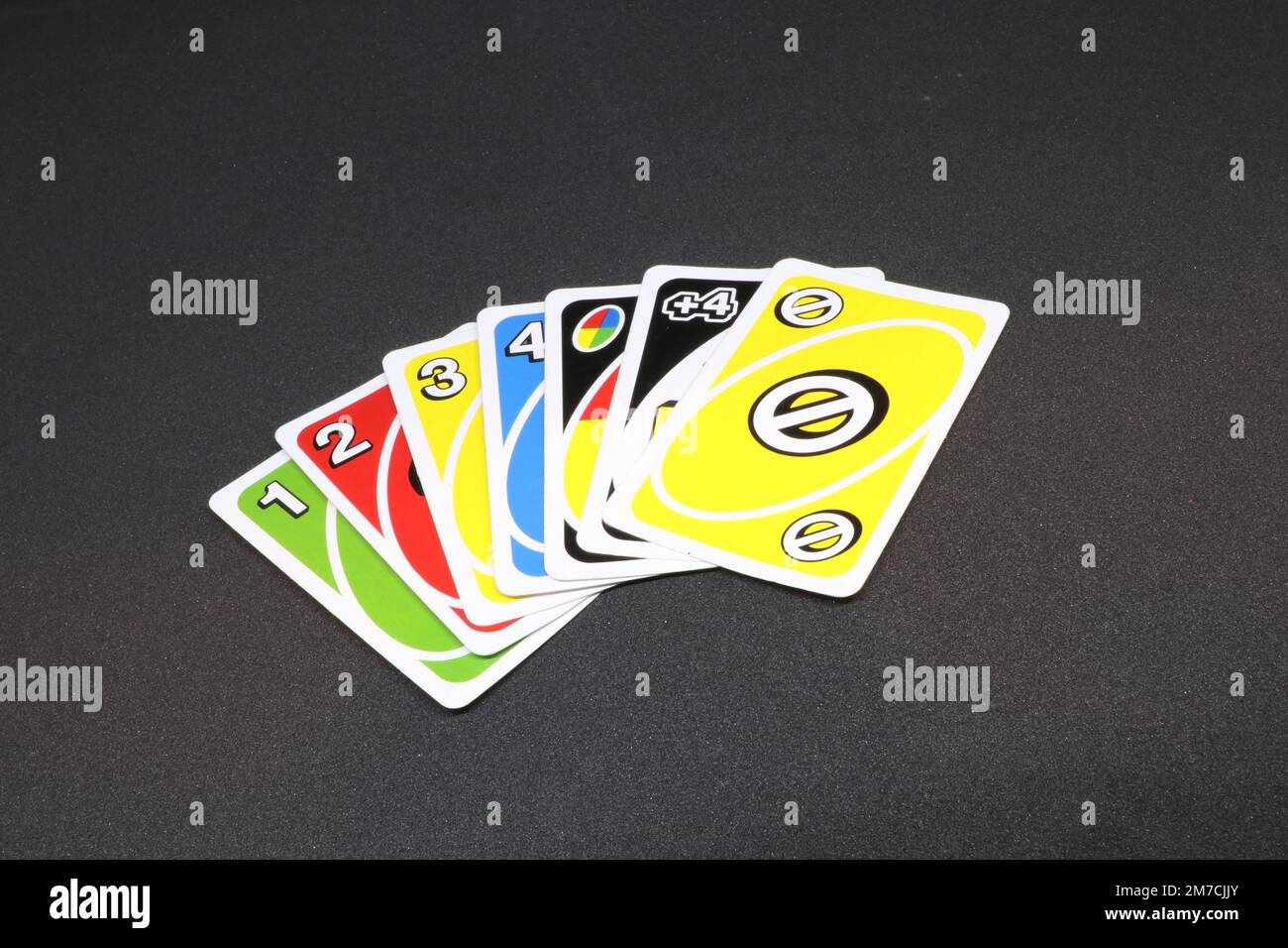 A spread of UNO cards isolated on a black background displaying red, yellow, green and blue Stock Photo