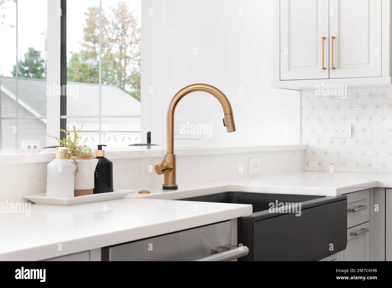 A beautiful sink in a remodeled modern farmhouse kitchen with a gold ...