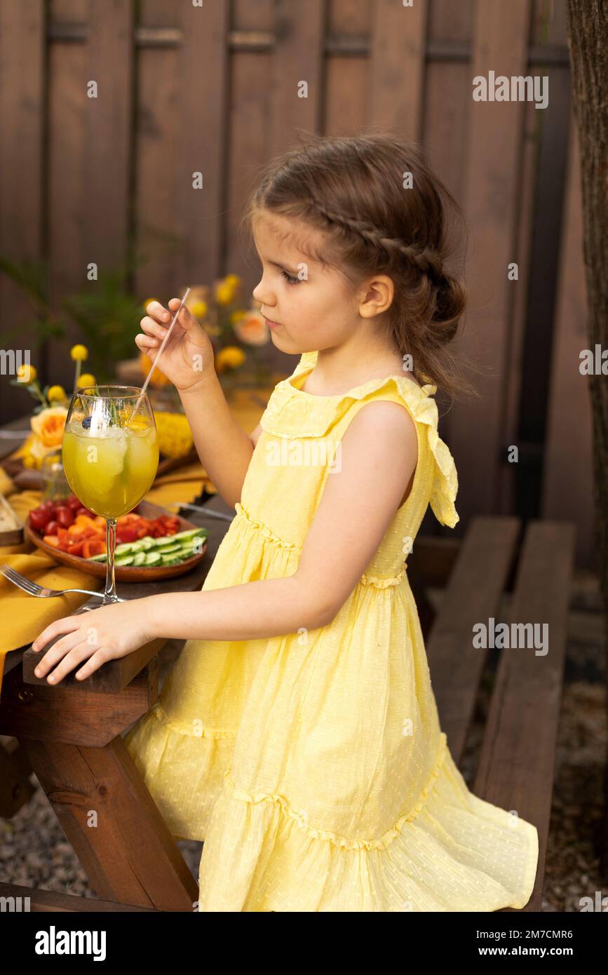 Portrait of little girl drinking juice in a glass, decorated with ...