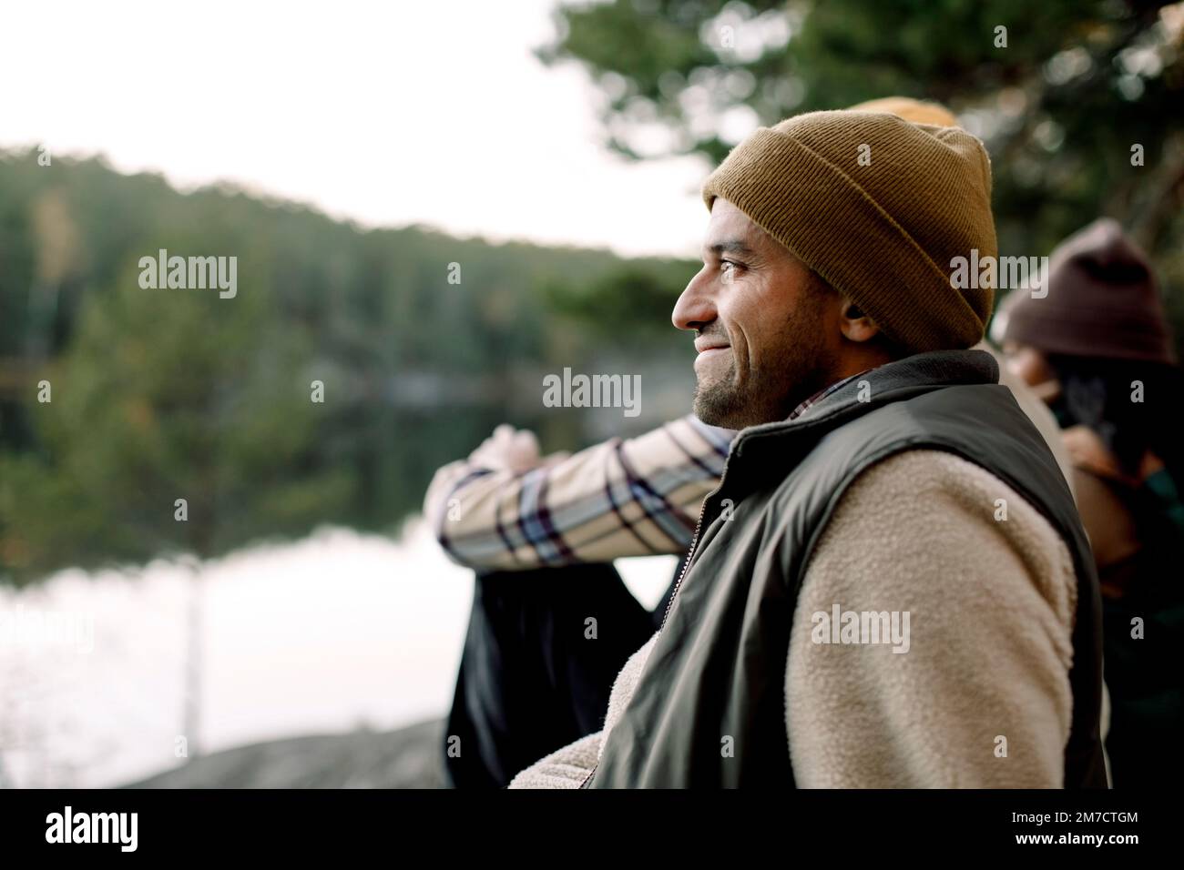 Side view of smiling man wearing knit hat by friends Stock Photo