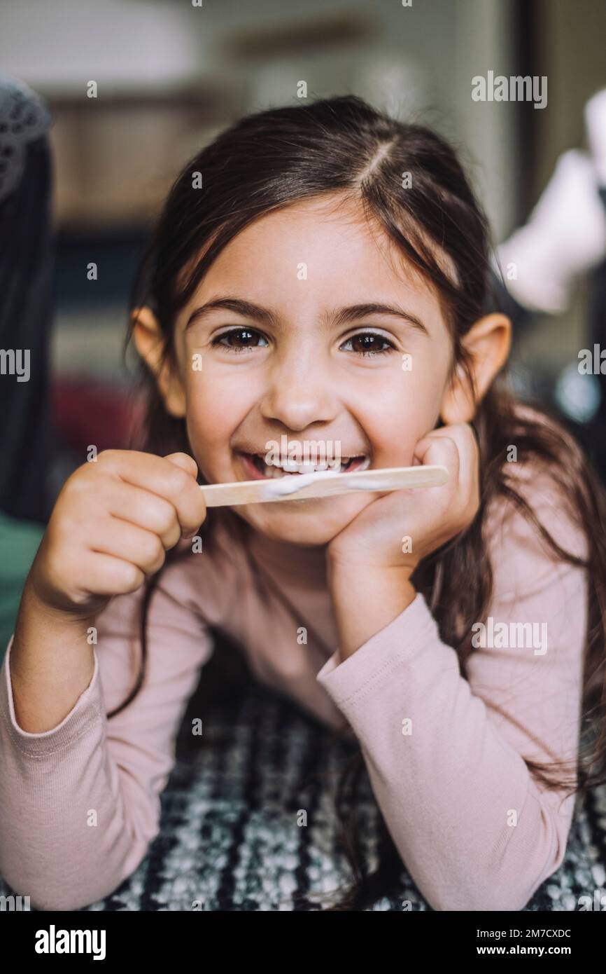 Portrait of smiling girl eating ice cream at day care center Stock