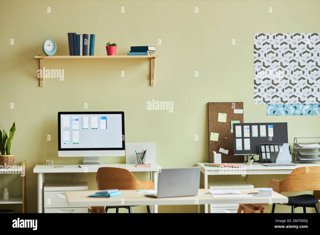 Background image of minimal office interior with computers on desks and pastel yellow wall, copy space Stock Photo
