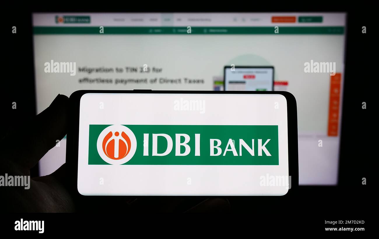 Person holding mobile phone with logo of Indian financial company IDBI Bank Limited on screen in front of web page. Focus on phone display. Stock Photo