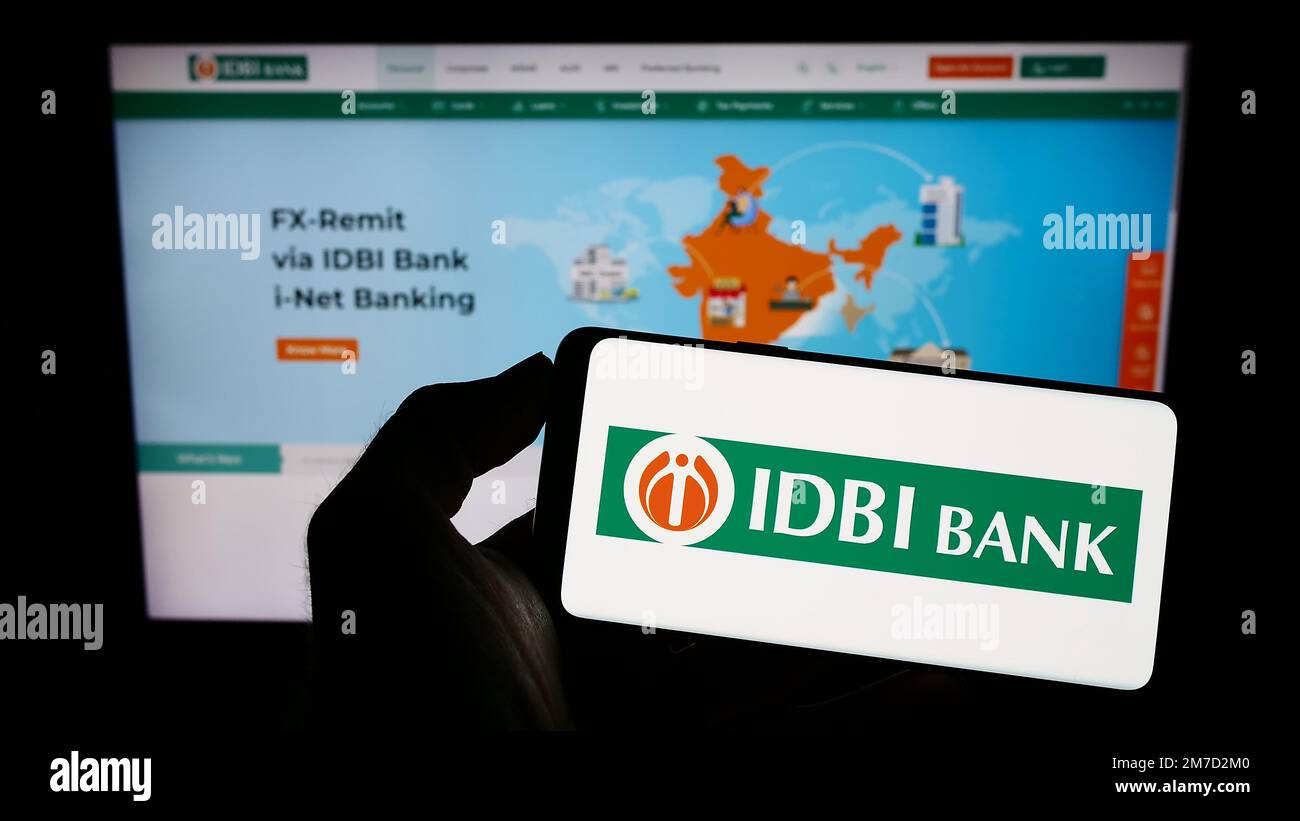 Person holding cellphone with logo of Indian financial company IDBI Bank Limited on screen in front of business webpage. Focus on phone display. Stock Photo