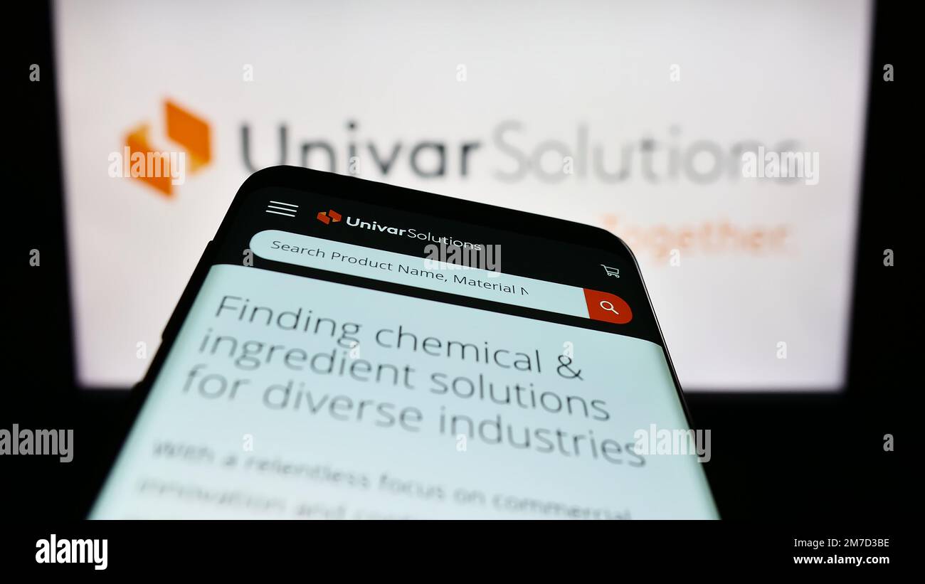Mobile phone with webpage of US distribution company Univar Solutions Inc. on screen in front of logo. Focus on top-left of phone display. Stock Photo