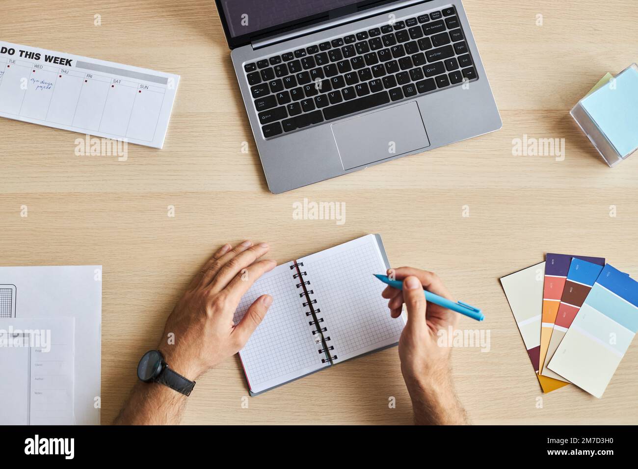 Top view of designers workplace with male hands writing in notebook, copy space Stock Photo