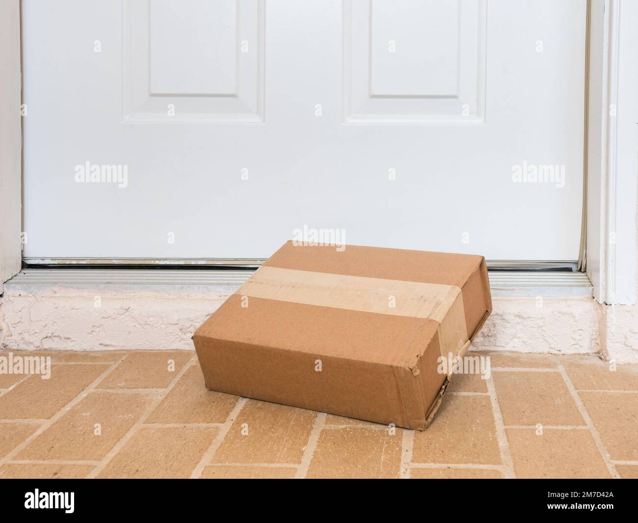 Package box delivered to a residential doorstep. Online order package delivery to the front porch of home. Stock Photo