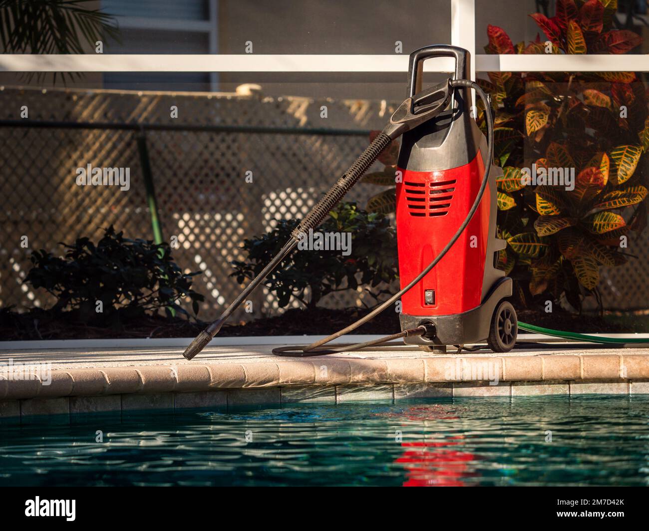 Electric powered pressure washer on swimming pool deck. Power wash cleaning service equipment. Stock Photo