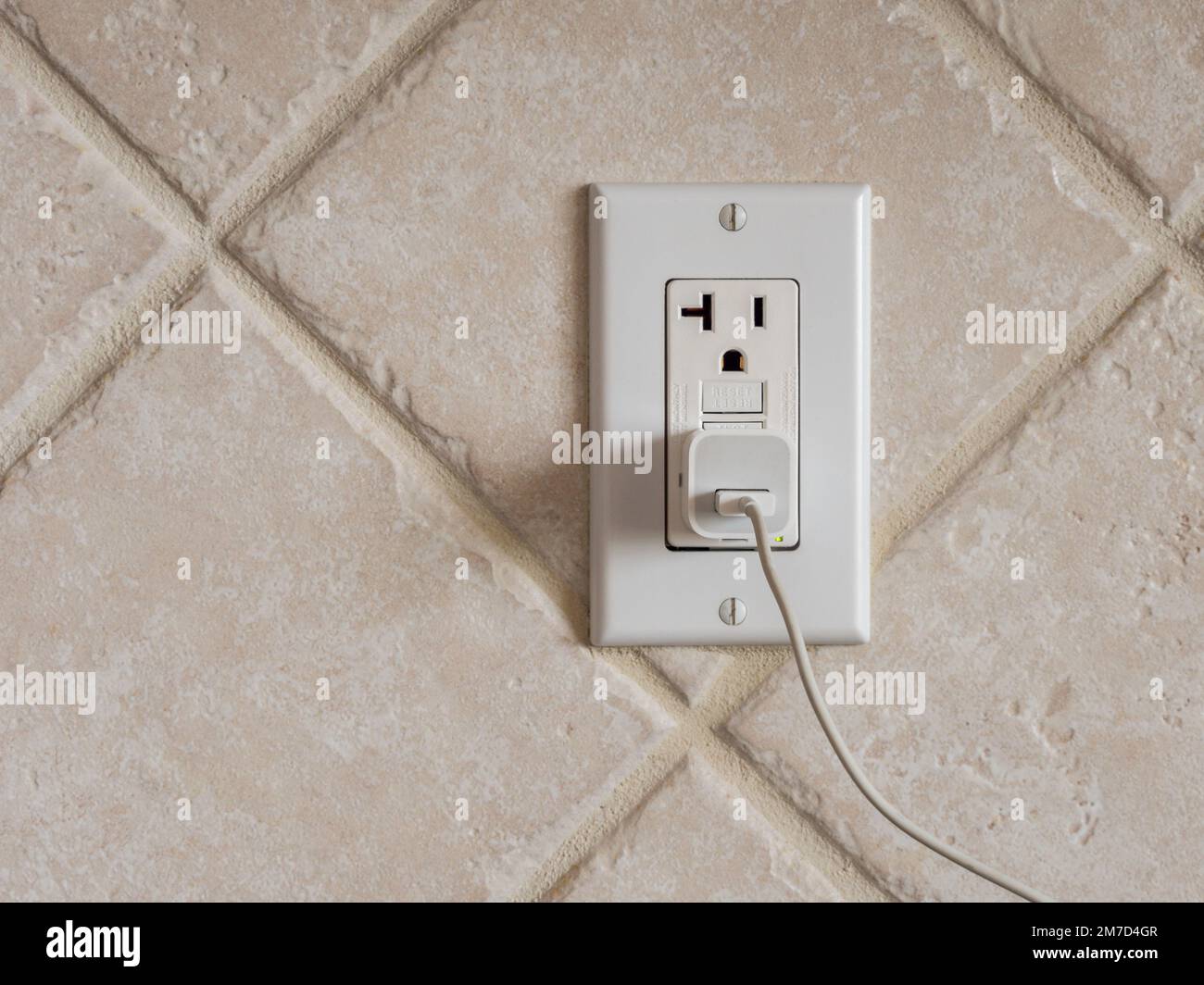 USB cell phone power adapter brick and cord in GFCI wall plug