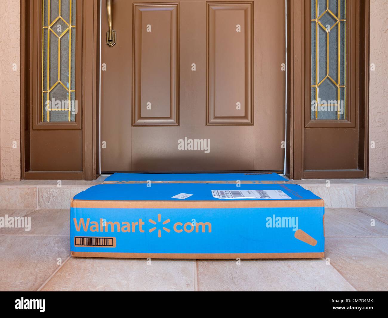 Walmart box delivered to residential doorstep. Walmart+ offers free package home delivery to it's members. Stock Photo