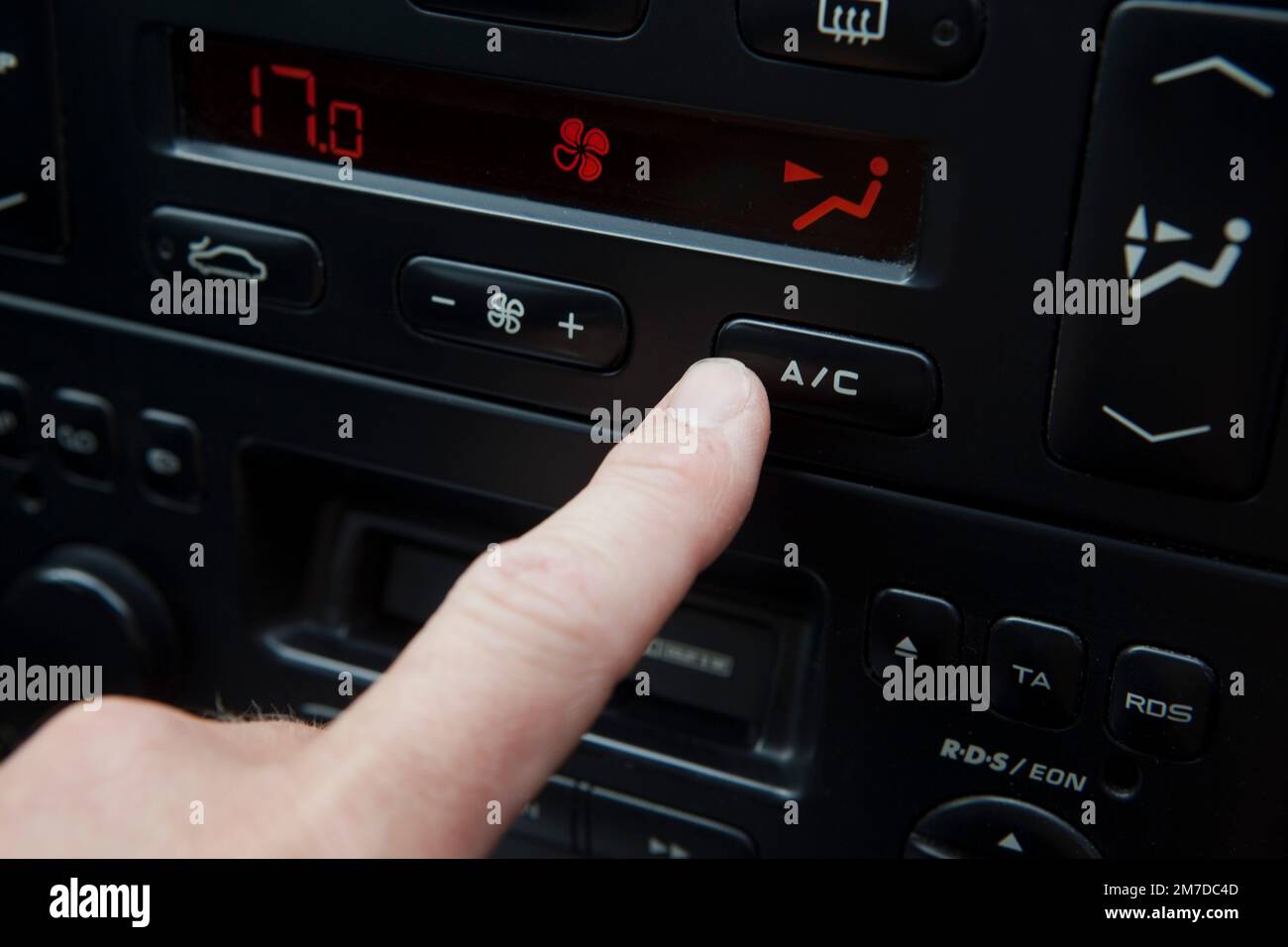 Air conditioning button in a car being pressed by the drivers finger