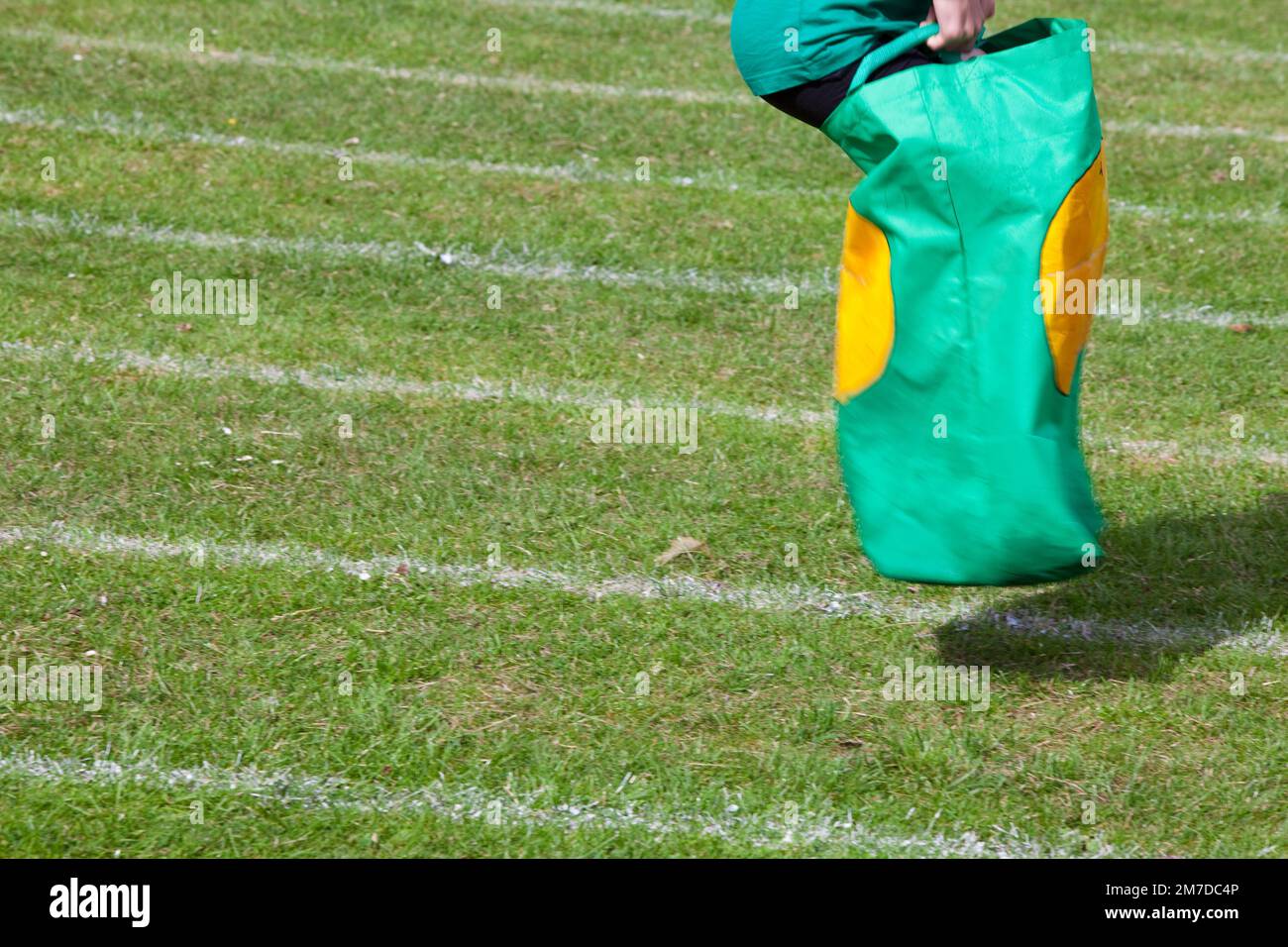 A child races down the school field during a sports day sack race competition, unidentified the kid flies down the track to the finish. Stock Photo