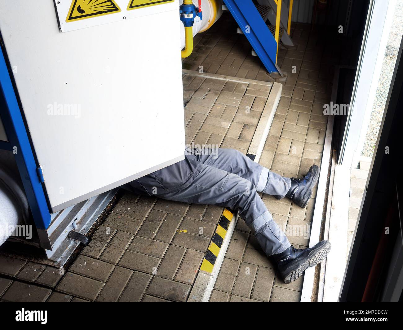 Accident. Electric shock to person. Out of electric panel stick out legs of worker. Electrician is electrocuted and lies on floor at production site. Compliance with labor protection.. Stock Photo