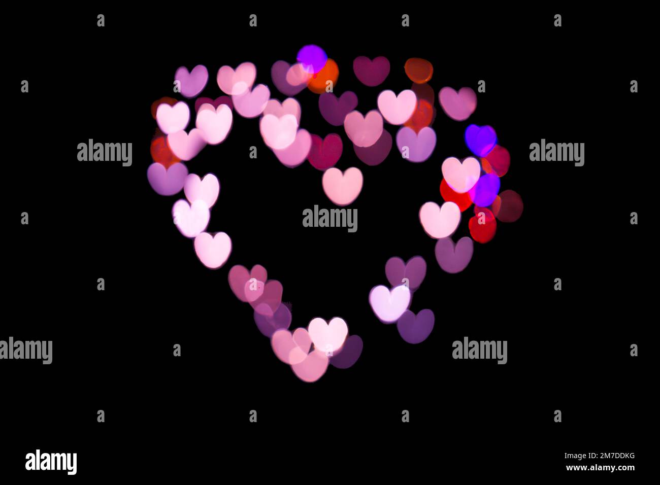 Heart shaped pink bokeh lights on black background, Love and Valentines day greetings Stock Photo