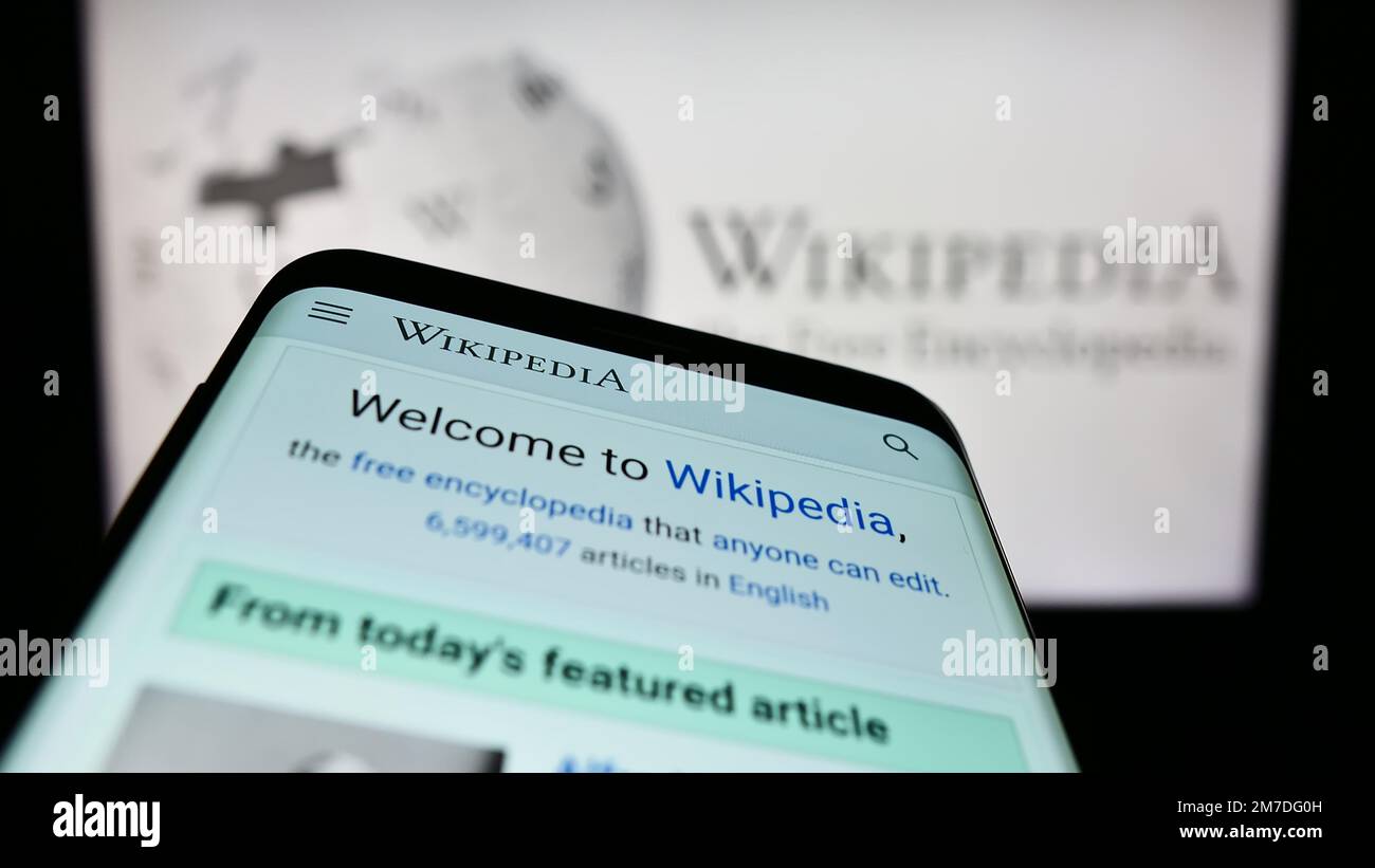 Mobile phone with website of online encyclopedia Wikipedia on screen in front of logo. Focus on top-left of phone display. Stock Photo