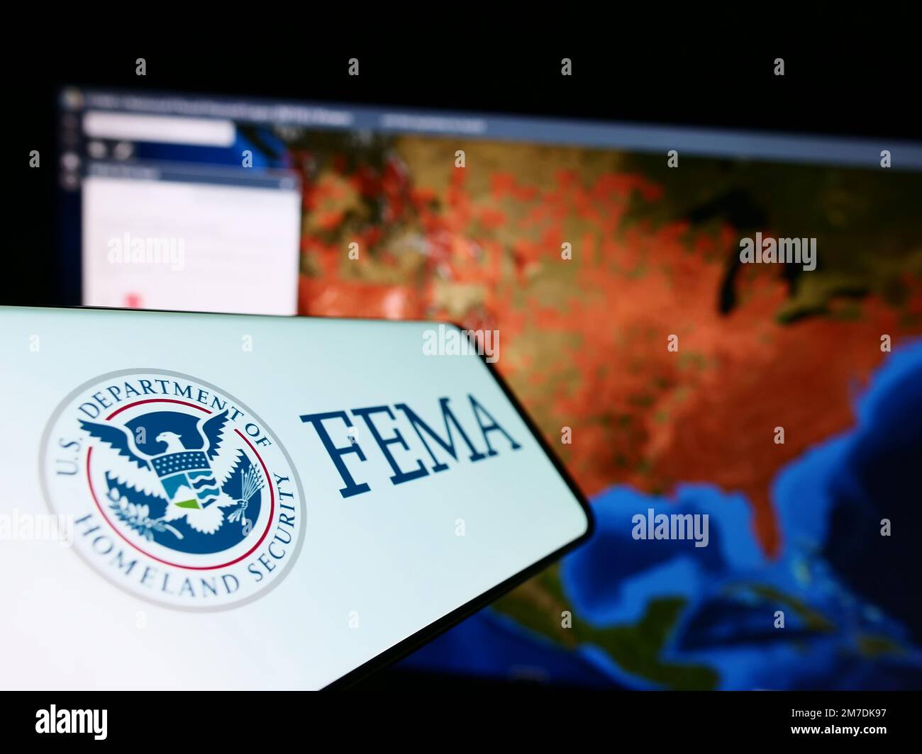 Mobile phone with seal of Federal Emergency Management Agency (FEMA) on screen in front of website. Focus on center-left of phone display. Stock Photo