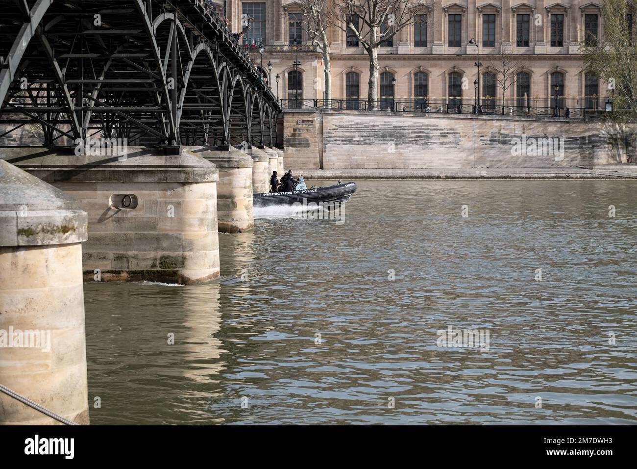 The River Seine in Paris and the river police passing by, the Pont des Arts, the Louvre in the background Stock Photo