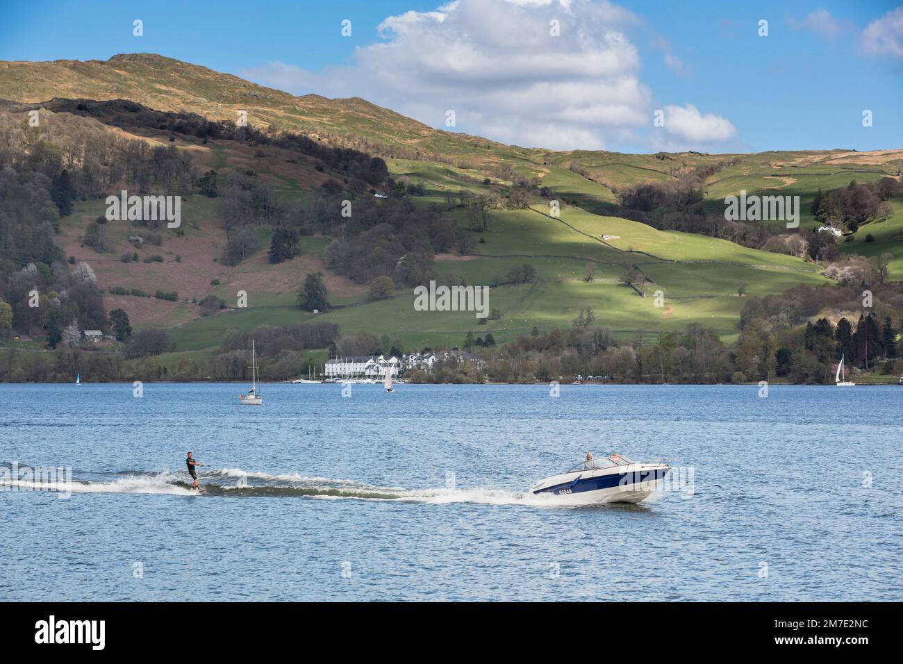 View across Lake Windermere with water skier being pulled bya speedboat. Stock Photo