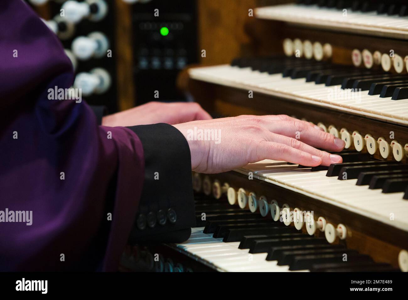 A pianists hands on an old chucth style organ palying the keyboards. Stock Photo