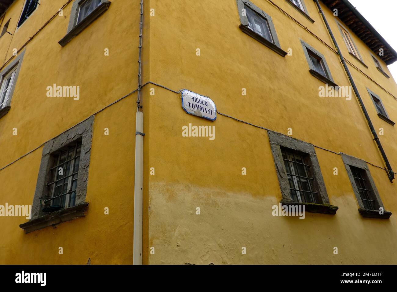 Street sign, on old Tuscan building, for Vicolo Tommasi, alley within the old town Lucca, Italy. Stock Photo