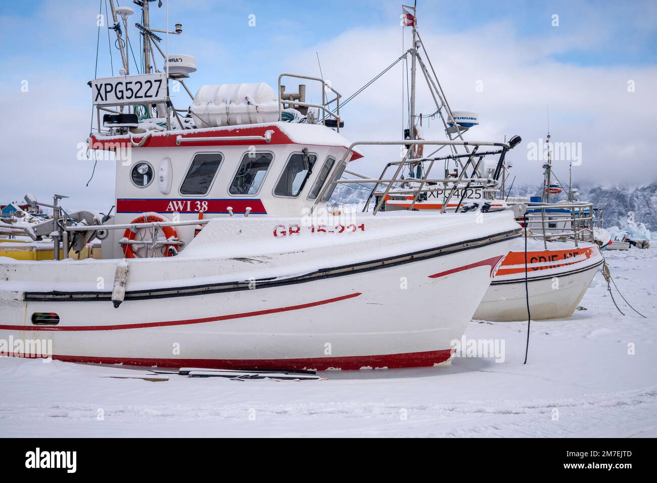 Fishing boats frozen into the sea ice in Uummannaq harbour in west Greenland Stock Photo