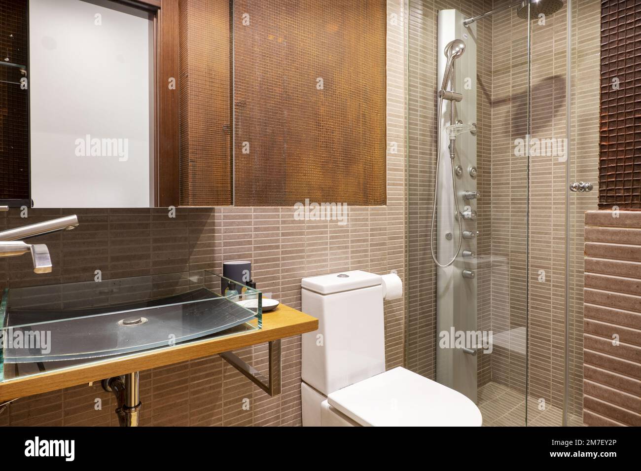 Small bathroom with light brown tile, with mirrored doors, and