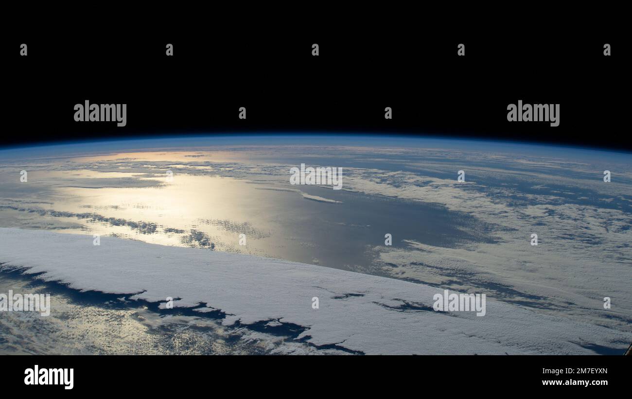 ISS - 01 January 2023 - The sun's glint beams off a partly cloudy Pacific Ocean in this photograph from the International Space Station as it orbited Stock Photo