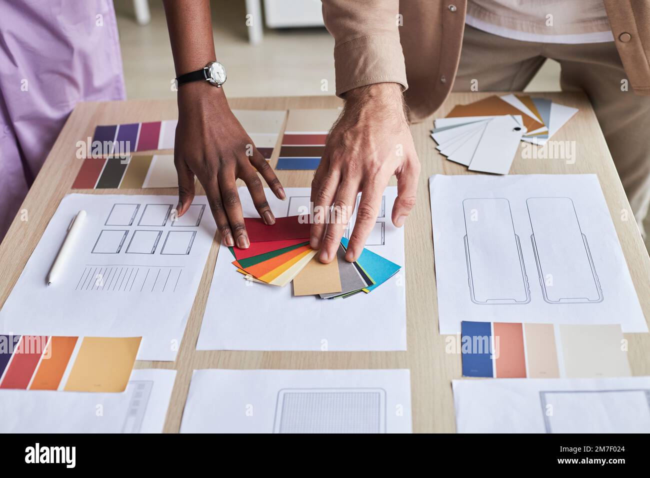 Close up of two designers choosing color swatches while working on UX project in office Stock Photo