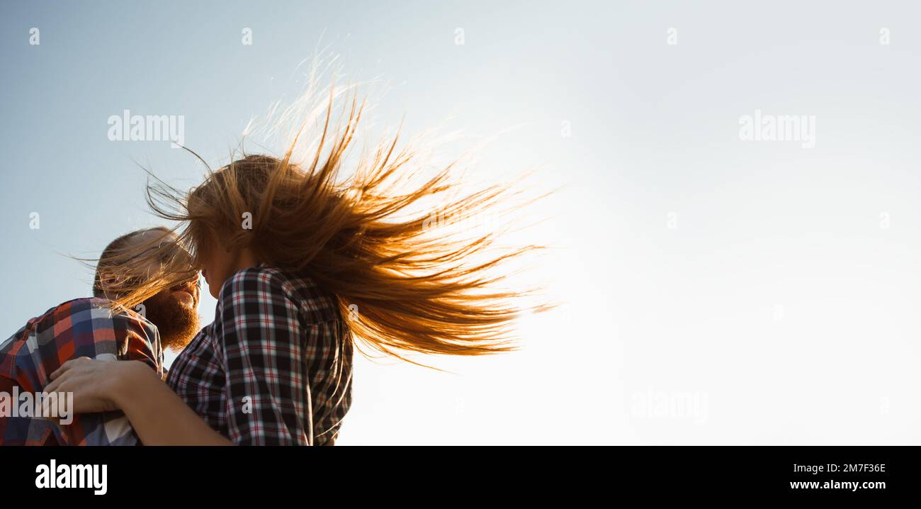 Bearded man and red-haired woman stand embracing at sunset. Stock Photo