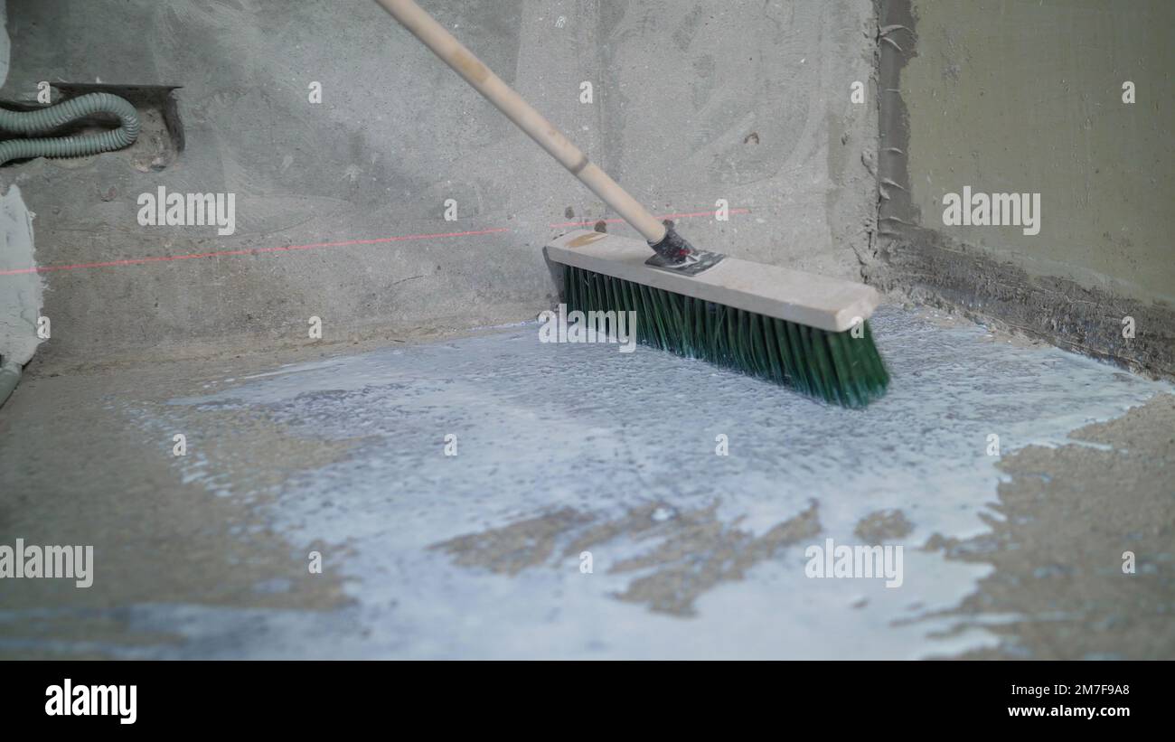 Primer for concrete floor. The master lays liquid soil on a concrete