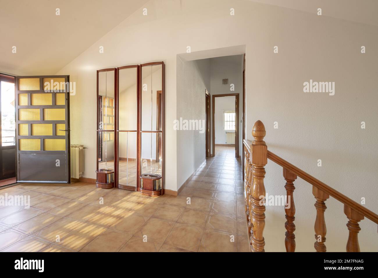 Interior stairs with wooden railing in a singlefamily residential home with long corridors and