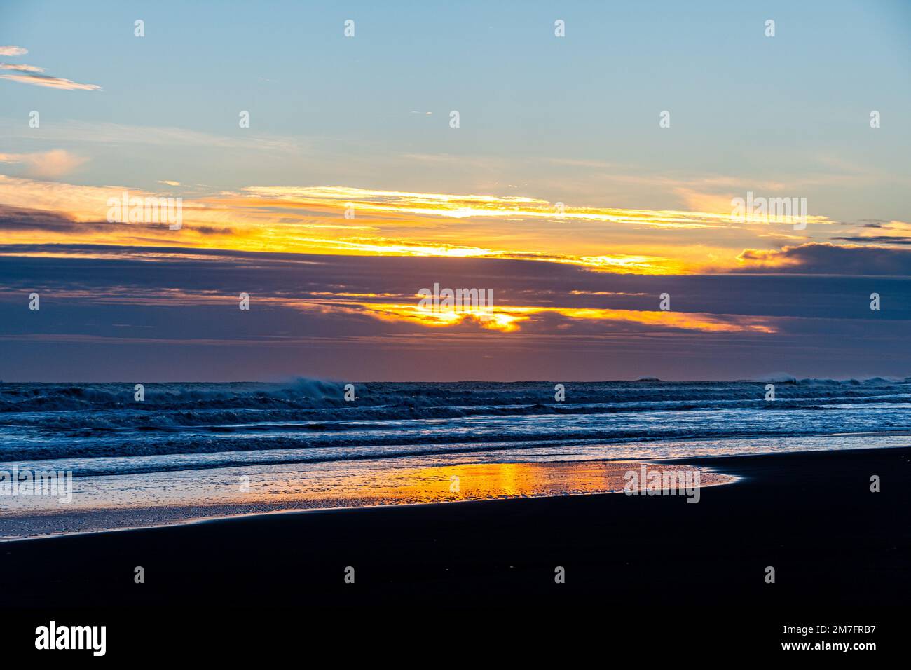 A beautiful sunset over a sea with waves crashing on the beach Stock ...