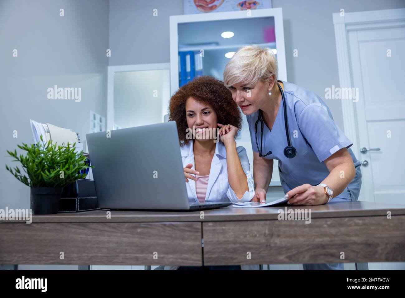 Two female doctors discussing something at the laptop in the clinic Stock Photo