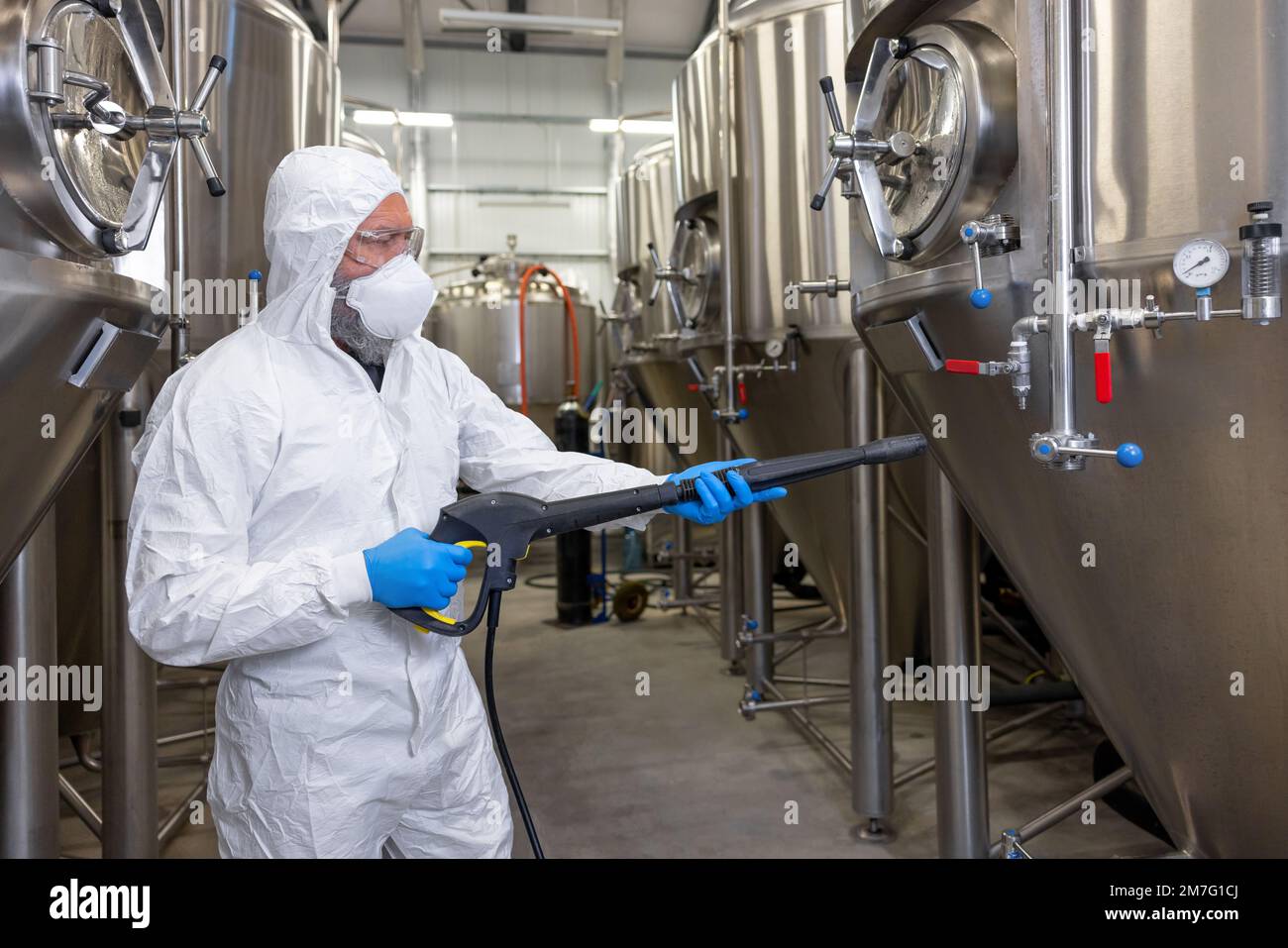 Experienced beer tech cleaning and sanitizing the brewing equipment