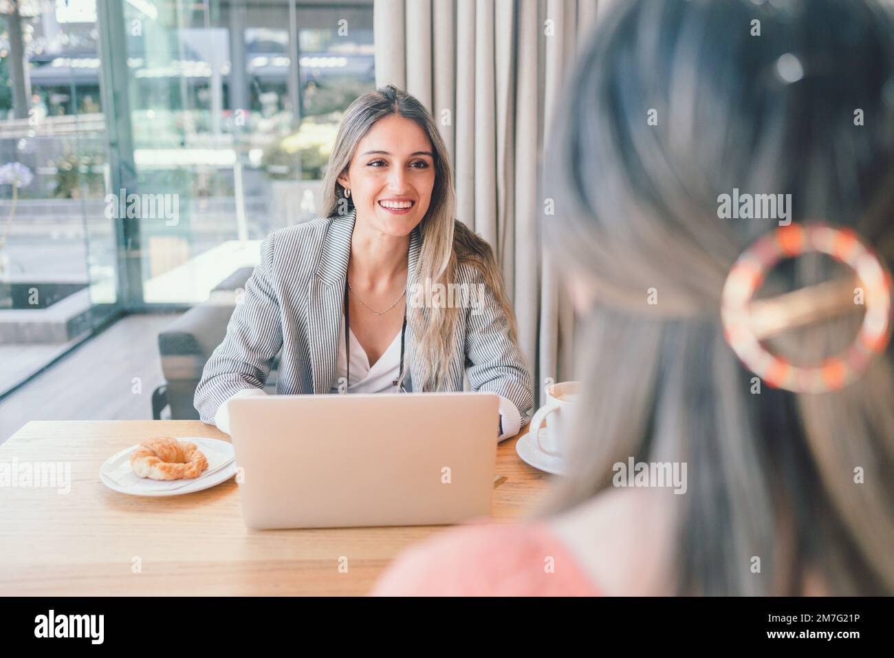 Happy millennial business woman using laptop, and having a interview with other woman in a workplace  Stock Photo