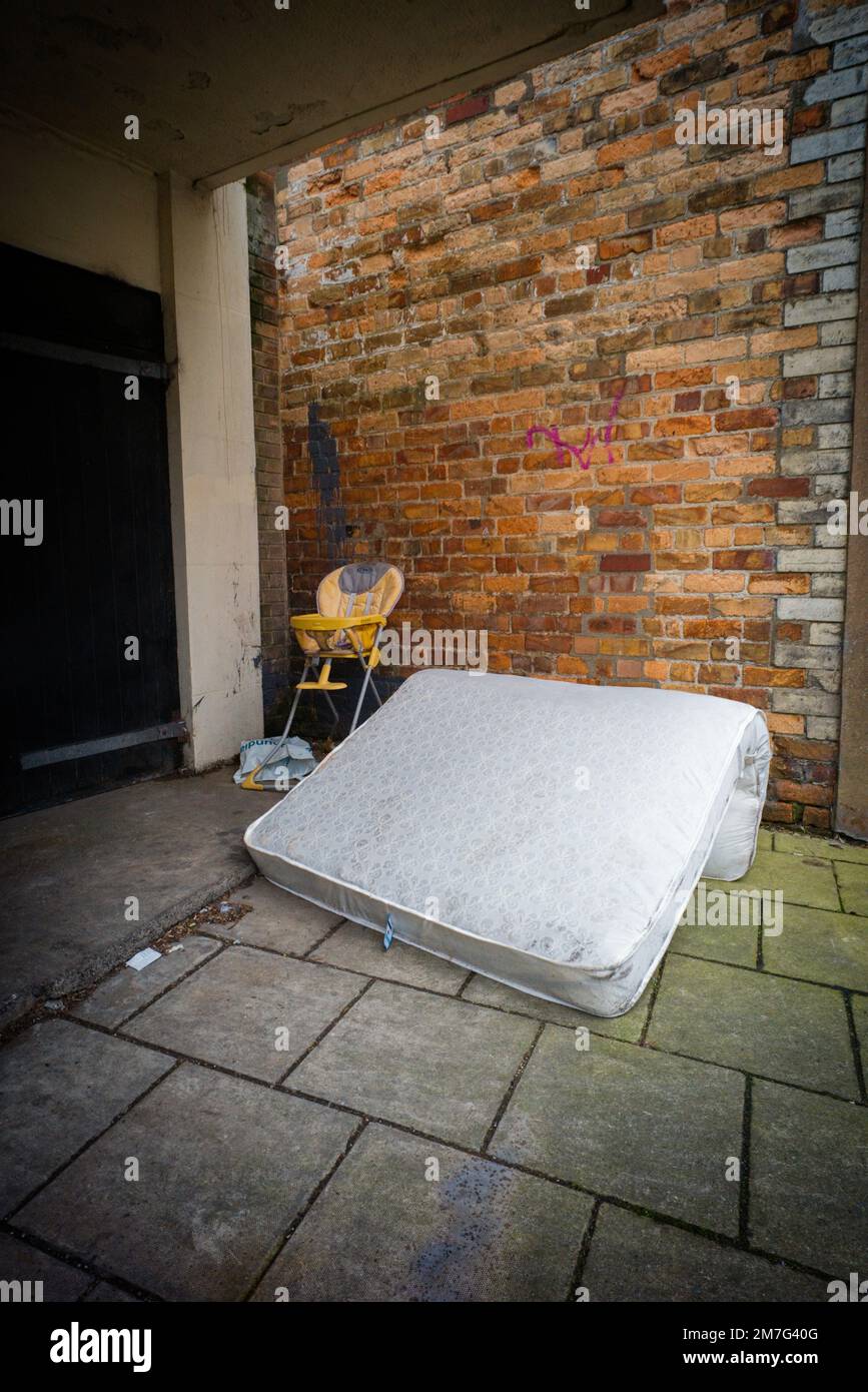 Mattress and high chair left out on street as urban flytipping Stock Photo