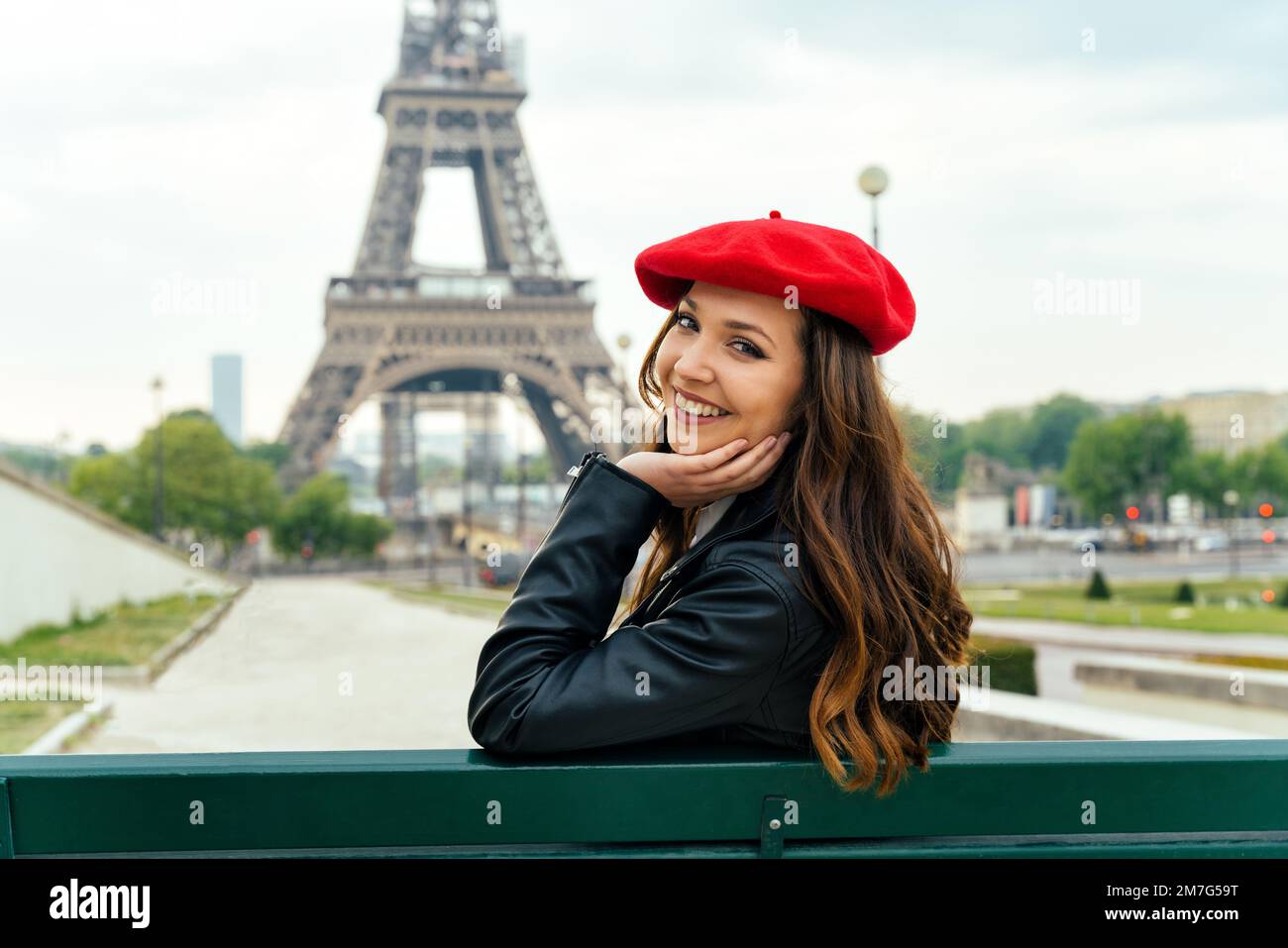 Beautiful young woman visiting paris and the eiffel tower. Parisian girl  with red hat and fashionable clothes having fun in the city center and  landma Stock Photo - Alamy