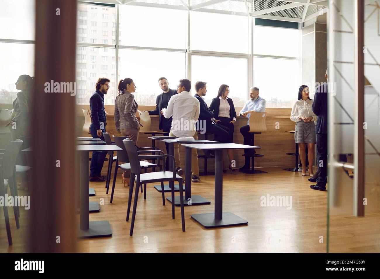 Office workers communicate with each other while having casual conversations during work break. Stock Photo