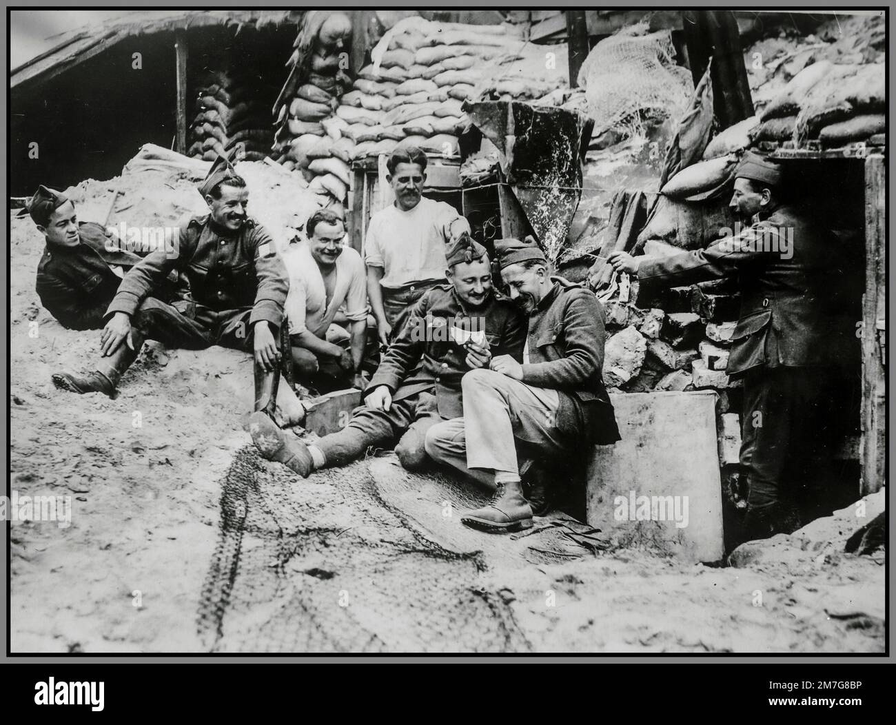 WW1 Belgian soldier at 'The Front' sharing his mail/ letter with his military colleagues from his 'Godmother' letter. Propaganda image from fortified trenches at The Front World War 1 Stock Photo