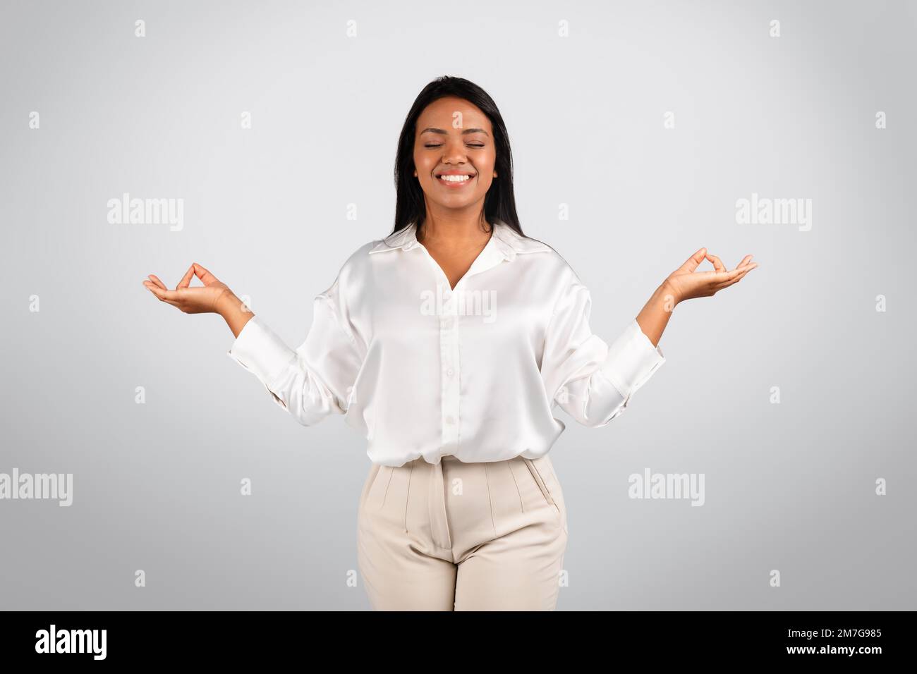 Glad serene millennial black female in white blouse with closed eyes meditation, enjoy spare time Stock Photo