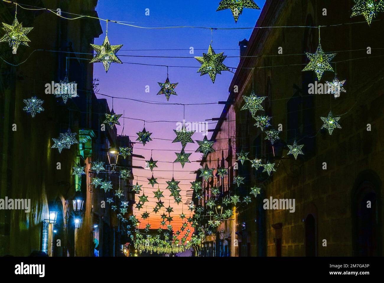 Colorful tin star decorations strung across historic buildings on Canal