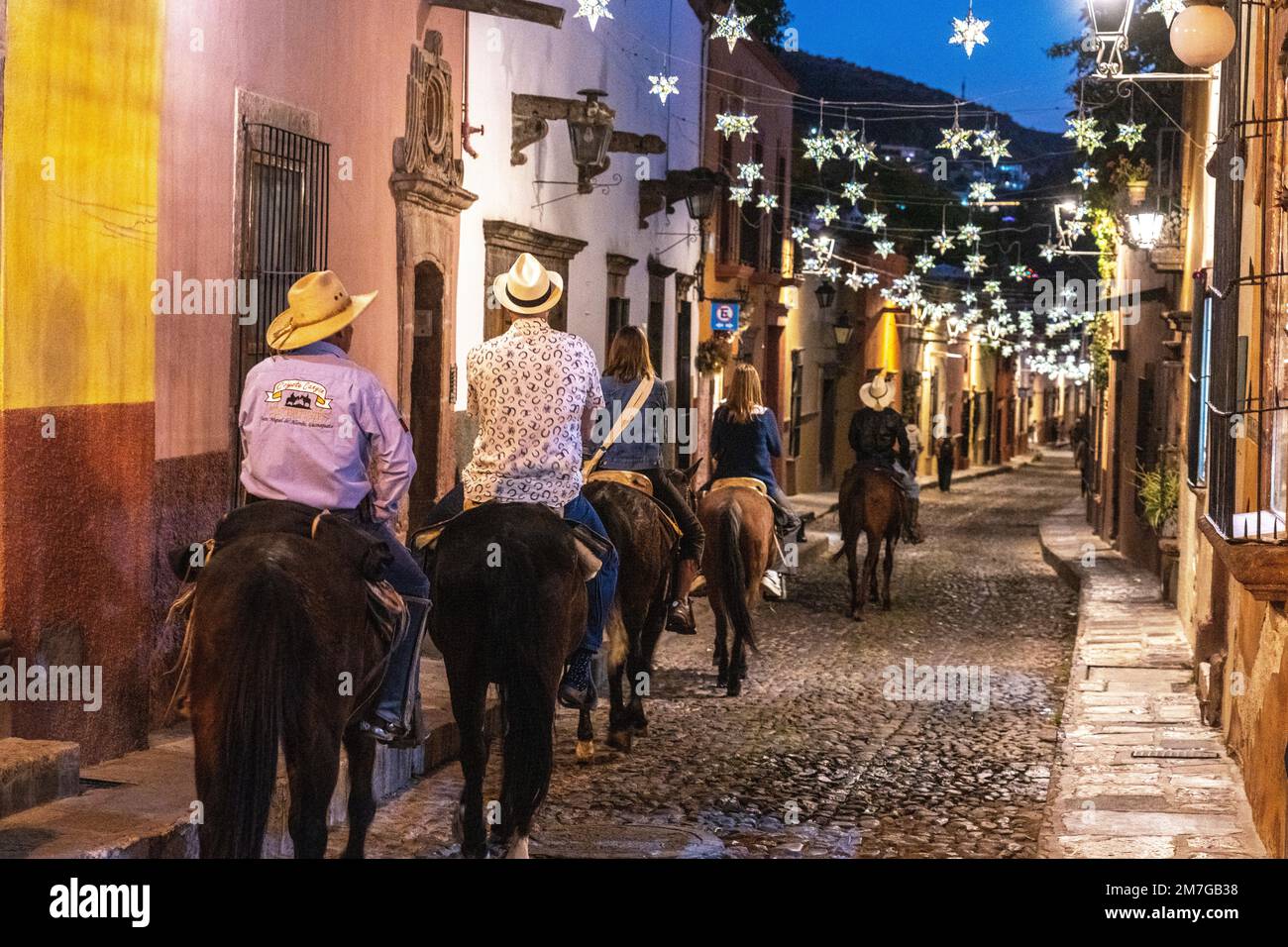 Horseback riding tour rides under the colorful tin star decorations strung across historic